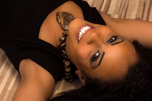 The beautiful smiling woman is lying down.