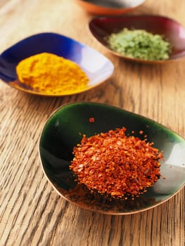Assortment of different spices in colorful copper bowls on a rustic wooden table