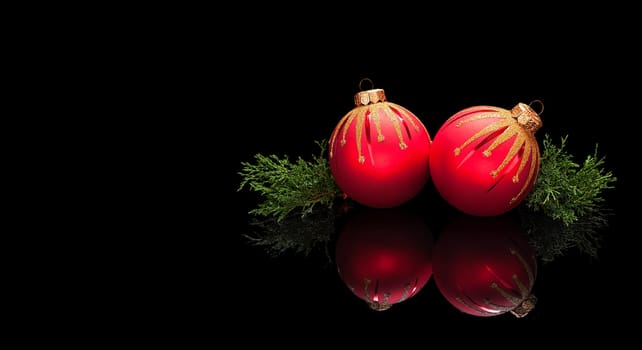 Christmas card template in luxury style, premium. Two red Christmas balls decorations with branches of an evergreen tree isolated on a black glossy background with real reflection. With space for your text