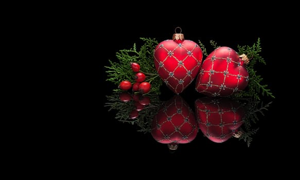Christmas card template in luxury style, premium. Two Christmas decorations in the shape of a heart with a branch of an evergreen tree and hips isolated on a black glossy background with real reflection. With space for your text