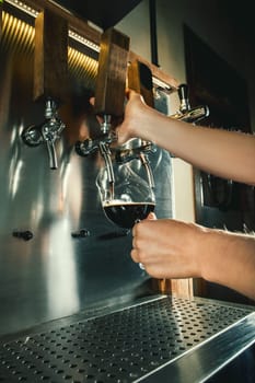 Hand of bartender pouring a large lager beer in tap. Soft, vintage instagram effect on photo