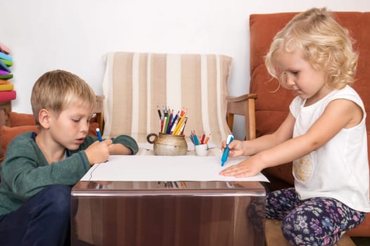 Boy and girl drawing on paper having creative time at home