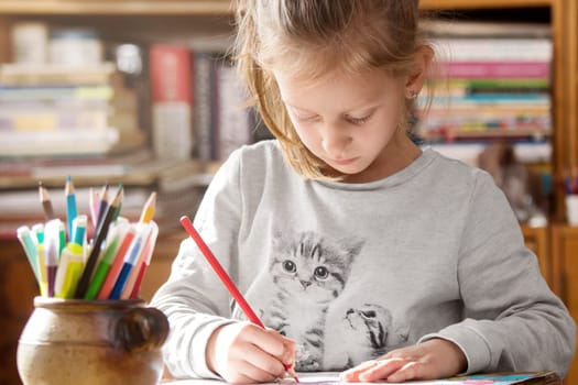 Girl coloring on paper having creative time at home