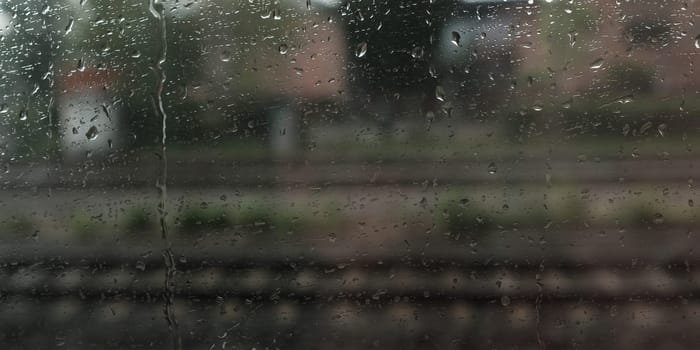 Raindrops on the window with blurred rails in the background