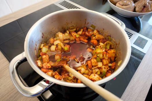 Carrots,celery and leeks stew in a pot with a wooden spoon on a stove