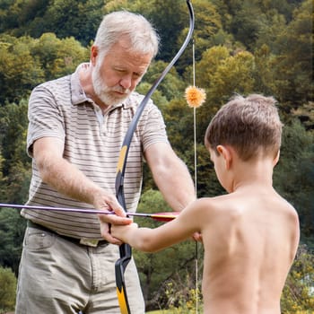 Older man showing a child how to place the arrow in the bow