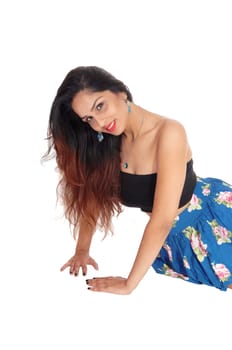 A young beautiful woman with long brunette hair and a blue skirt.and black corset sitting on the floor, isolated for white background.