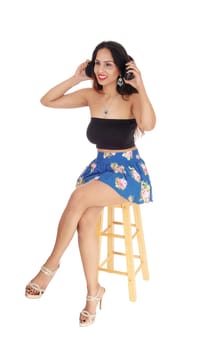 A beautiful happy woman with her headphone listening to music,.sitting on a chair, isolated for white background.