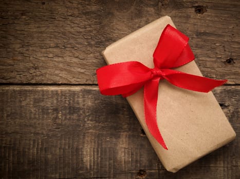 Gift box with a red bow on a rustic wooden background
