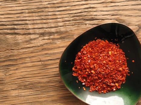Cooking ingredients, chilli flakes in a green bowl on a wooden rustic table