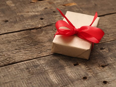 Gift box with a red bow on a rustic wooden background