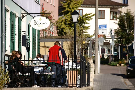 Nieder-Olm,Germany - October 14,2017: Visitors to Café Blums sit in the sunshine outside on a veranda on October 14,2017 in Nieder-Olm.