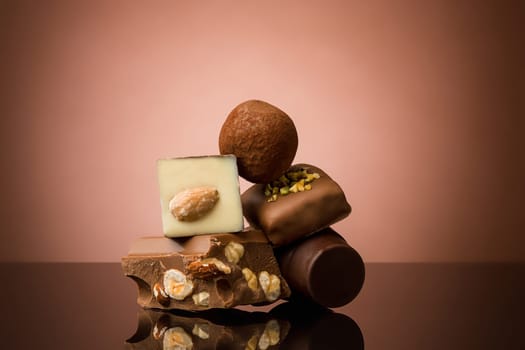 Pile of broken chocolate on table against brown studio background