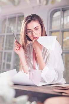 The female fashion designer working in studio sitting on the desk