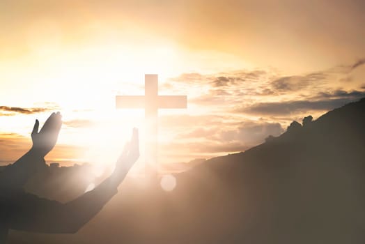 Human hands raising hand while praying to jesus on sunset background