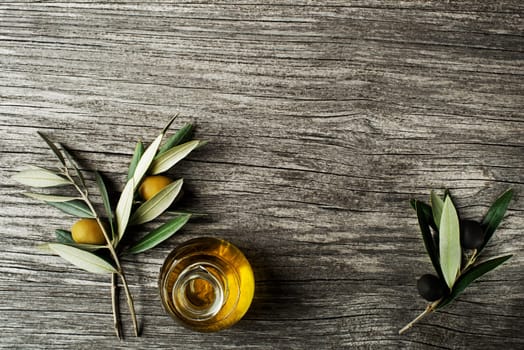 Olive oil and olive branch on a wooden background