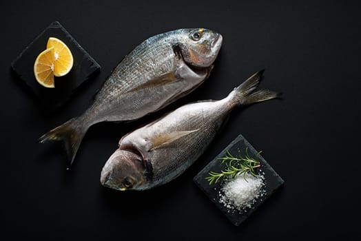 Delicious fresh fish gilt-head on dark background. Healthy food diet or cooking concept