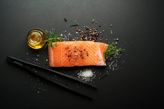 Raw steak of salmon fish with spices and herbs on black background