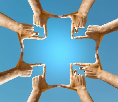 Hands forming a cross against the blue sky
