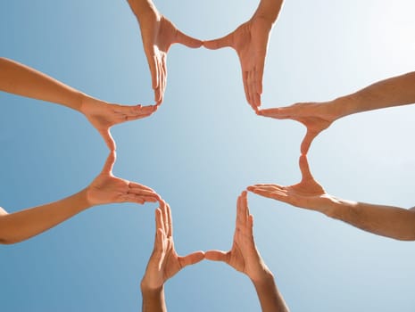 Hands forming a cross against the blue sky
