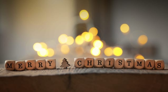 Christmas background with the words Merry Christmas on a wooden table, blurred Christmas lights in the back