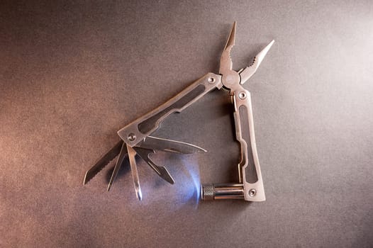 Combined pliers, multifunctional, with flashlight. Against the background of a gray texture.