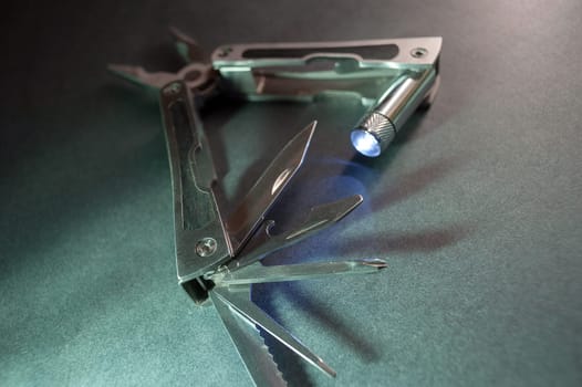 Combined pliers, multifunctional, with flashlight. Against the background of a gray texture.