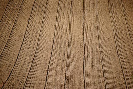The tracks and furrows caused by tractor tires in a field.