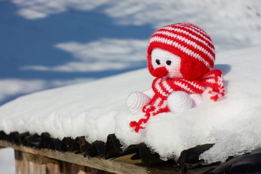 Self-crocheted snowman sits in the snow