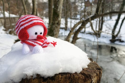Crocheted snowman sits in the snow