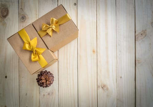 Christmas brown gift boxes with gold bow and pine cone on wooden background for copy space