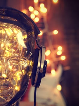 Headphones on a glass head with Christmas lights, Christmas music, Rock guitar with lights in the background