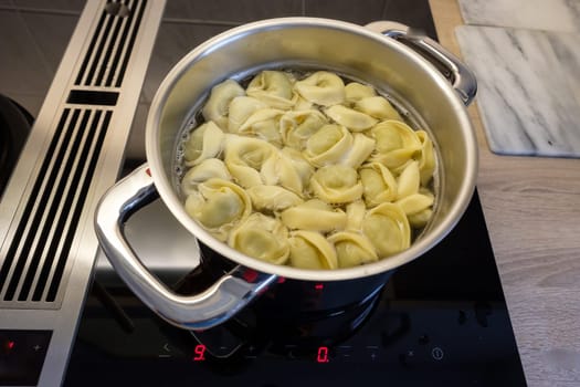 Cooking pot with tortellini on a hob with extractor hood