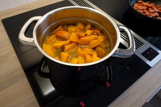 Pumpkin in a saucepan on an induction cooker with extractor hood