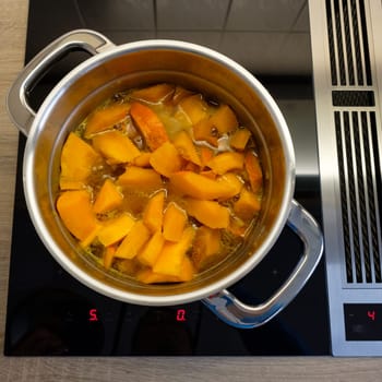 Pumpkin in a saucepan on stove with induction and cooktop extraction
