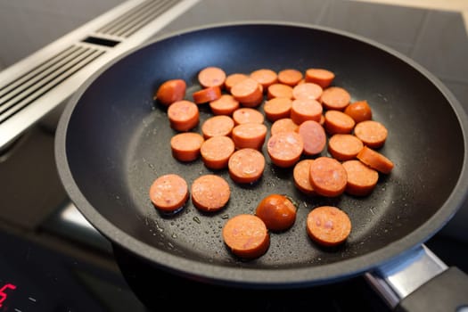 Debreziner sausage in frying pan on hob with cooktop extractor