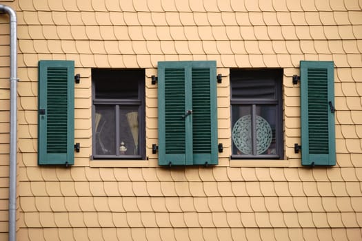 Open shutters on a striking façade of yellow shingles.