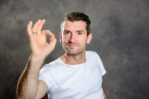 friendly young man show OK sign in front of gray background
