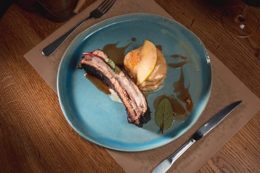 The grilled pork ribs on dark plate on wooden table