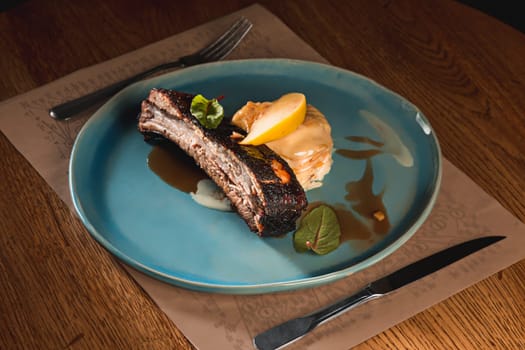 The grilled pork ribs on dark plate on wooden table