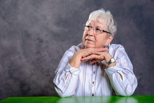 gray hairy elderly woman with glasses looking relaxed