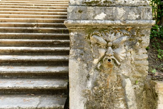 A marble mask on the side of a stair