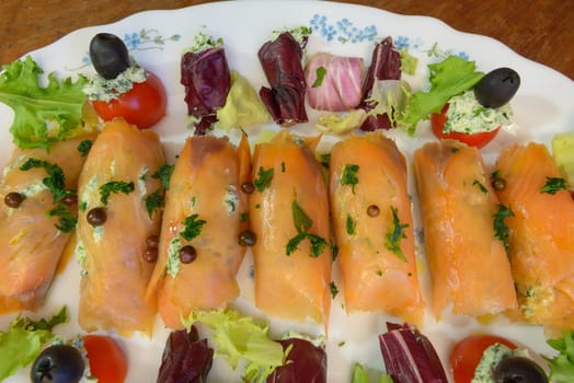 Wonderful and tasty smoked salmon rolls with salad tomatoes olive and cheese