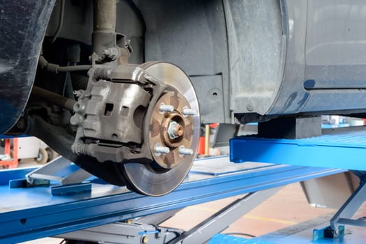A car ready for fix on a workshop bridge, brakes are visible