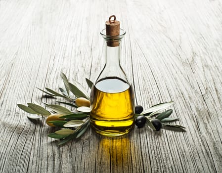Olive oil and olive branch on a wooden background