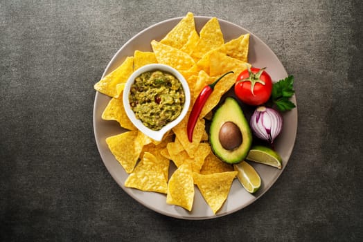 Guacamole sauce with fresh ingredients and corn nachos chips