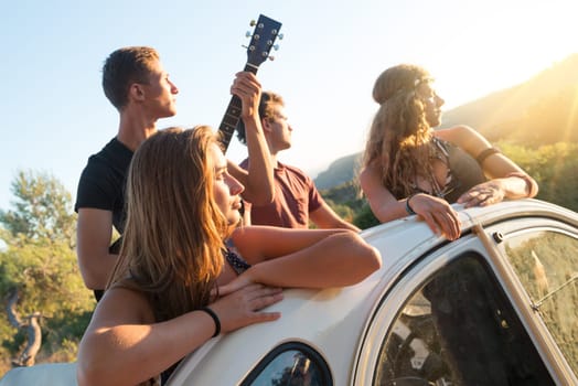 Group of happy people in a car at sunset in summer.
