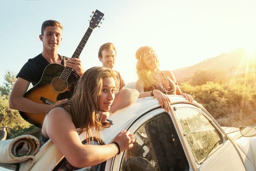 Group of happy people in a car at sunset in summer.