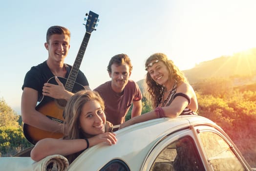 Group of happy people in a car at sunset in summer.