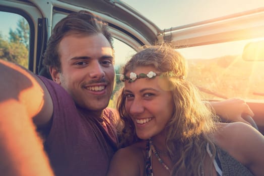 Happy couple in a car enjoying sunset.
